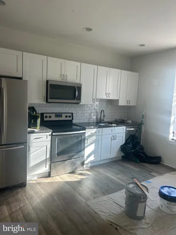 a kitchen with granite countertop a refrigerator and a stove top oven