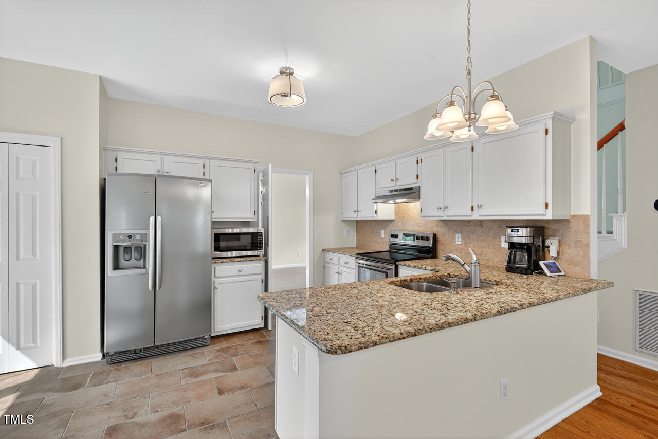 8825 Kirkstall Court Raleigh, NC 27615 - Photo 17 of 49 a kitchen with granite countertop stainless steel appliances a refrigerator a stove a sink and a center island