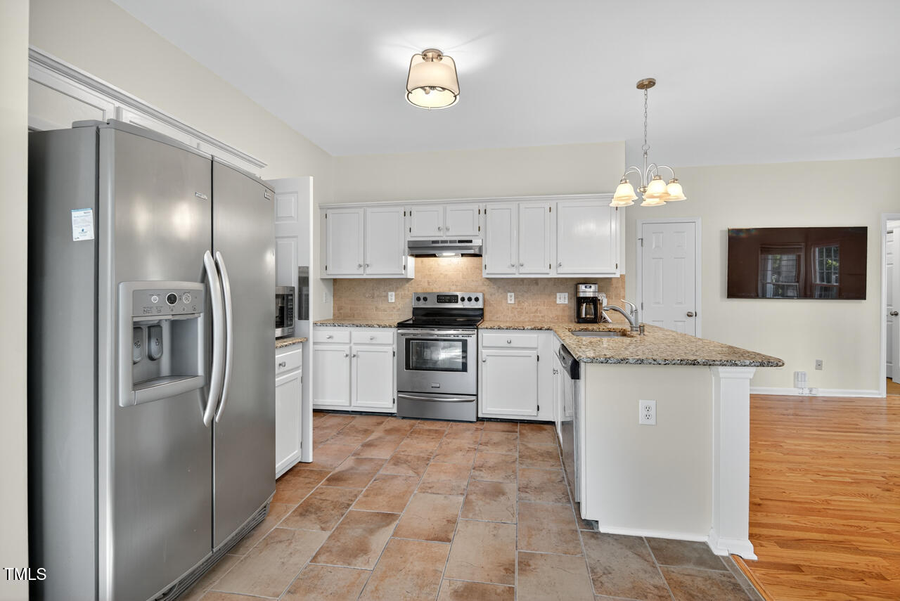 8825 Kirkstall Court Raleigh, NC 27615 - Photo 21 of 49 a kitchen with granite countertop a refrigerator stove top oven and cabinets