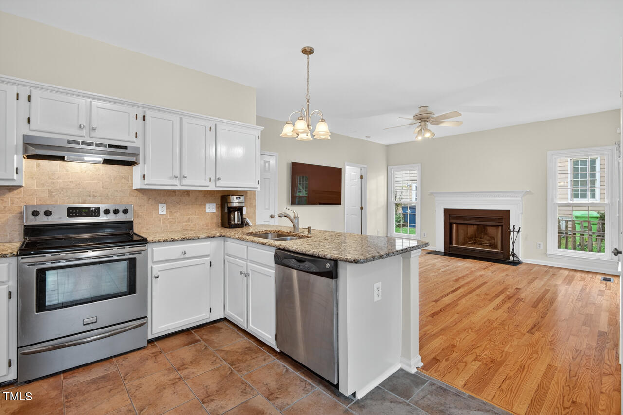 8825 Kirkstall Court Raleigh, NC 27615 - Photo 22 of 49 a kitchen with granite countertop a stove top oven sink and cabinets