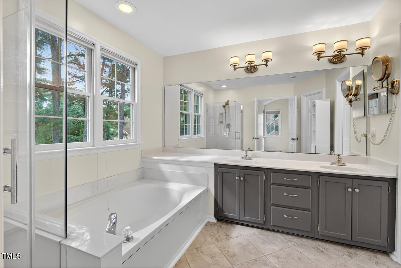 8825 Kirkstall Court Raleigh, NC 27615 - Photo 30 of 49 a bathroom with a tub a double vanity sink and a large mirror