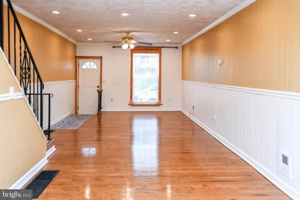 a view of an empty room with wooden floor and stairs
