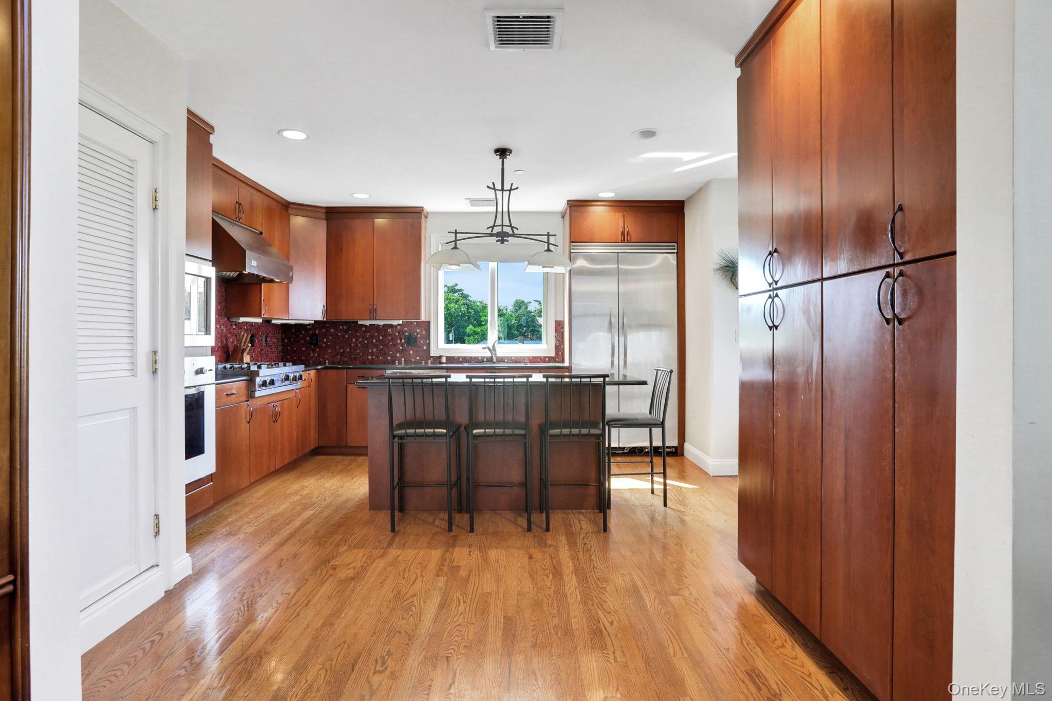 2 Harbor Lane, Unit 301 New Rochelle, NY 10805 - Photo 9 of 33 a kitchen with stainless steel appliances a dining table chairs a refrigerator and cabinets