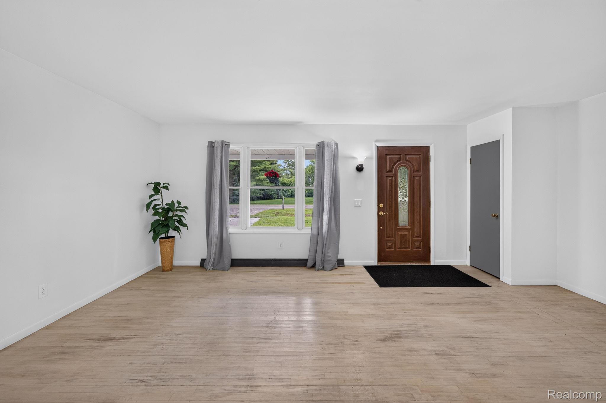 9288 Hilda Lane Flushing, MI 48433 - Photo 10 of 50 Entryway featuring a decorative wood door with glass insert, light wood-finish flooring, white baseboards, and a window with natural light