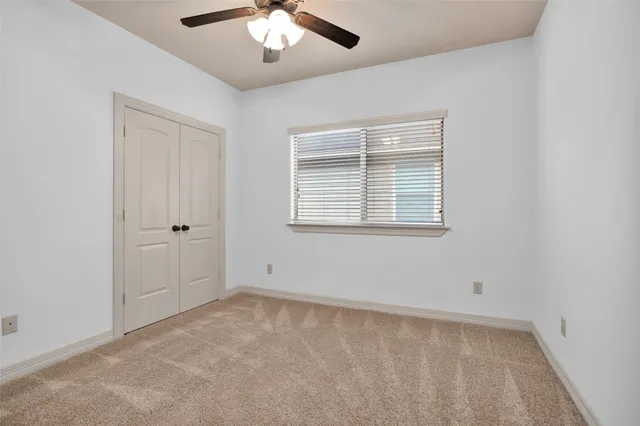 an empty room with windows and chandelier fan