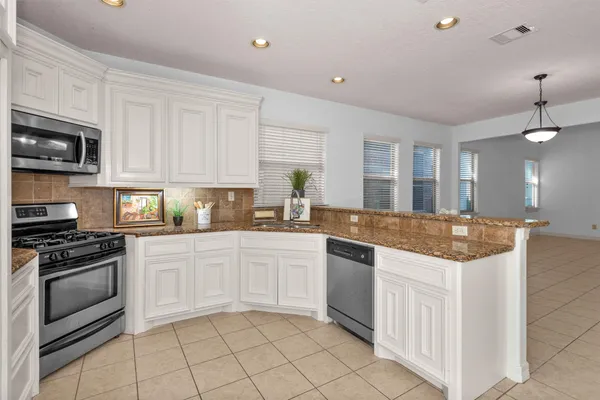a kitchen with granite countertop a sink and white cabinets