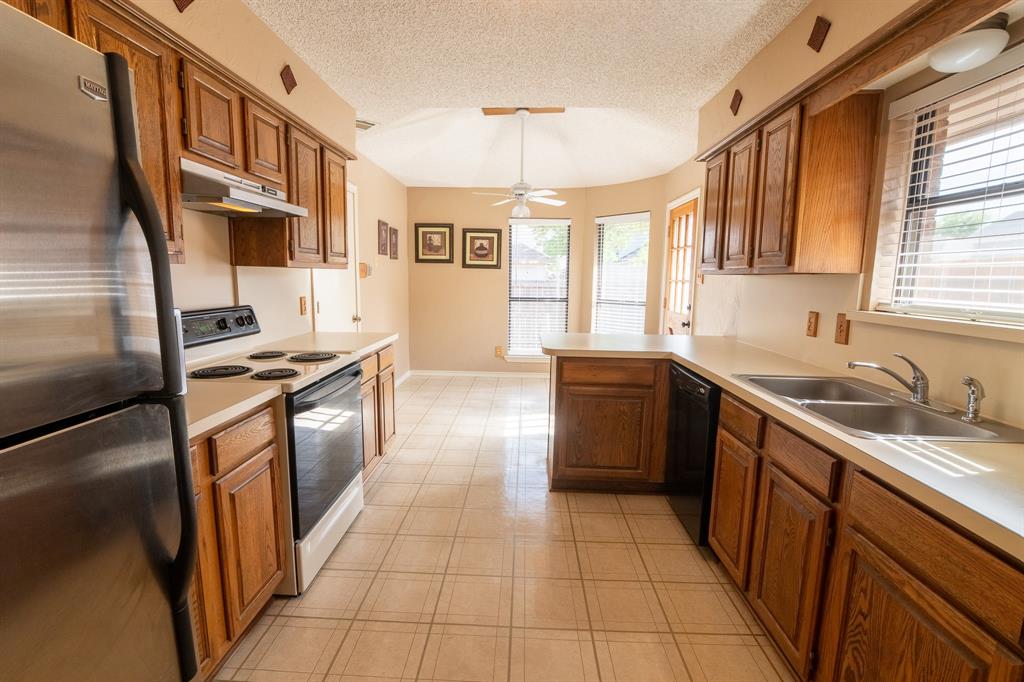 2028 Falcon Ridge Drive, Unit B Carrollton, TX 75010 - Photo 7 of 11 Kitchen featuring freestanding refrigerator, electric range oven, light countertops, a textured ceiling, and wood finish cabinetry