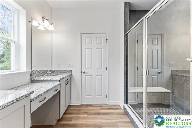 a spacious bathroom with a granite countertop sink a mirror and a shower