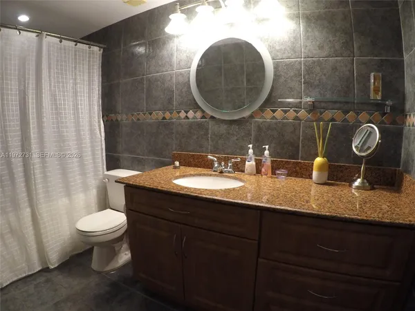 a bathroom with a granite countertop toilet a sink and a mirror