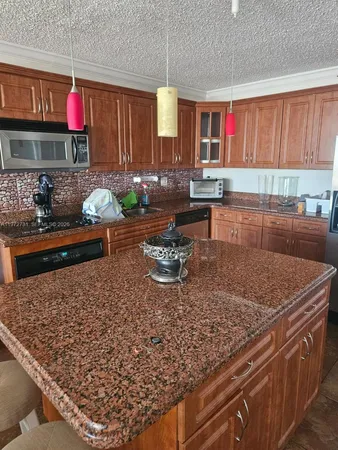 a kitchen with stainless steel appliances granite countertop a stove a sink and a wooden cabinets