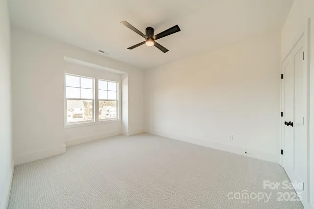 an empty room with ceiling fan and windows