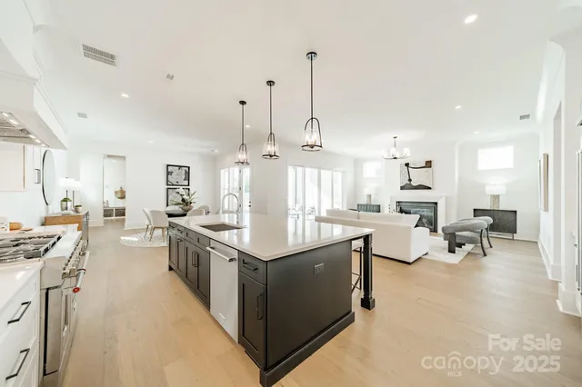 a large kitchen with stainless steel appliances kitchen island granite countertop a large counter top a stove a chimney a sink and dining room view