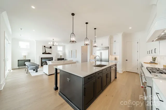 a large kitchen with stainless steel appliances kitchen island a large counter top a sink a stove and a refrigerator