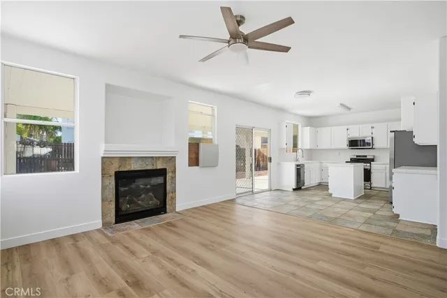 a view of a livingroom with a fireplace a ceiling fan and wooden floor