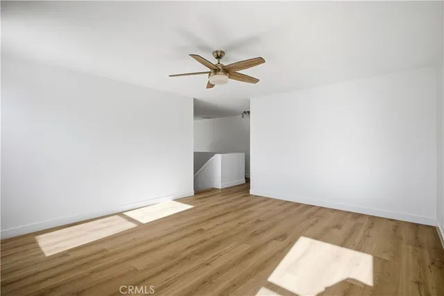 a view of a room with wooden floor and a ceiling fan