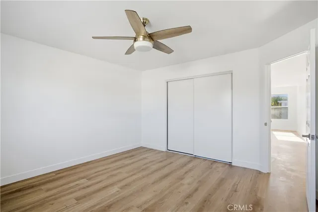 an empty room with wooden floor ceiling fan and windows