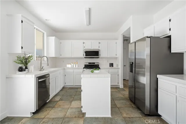 a kitchen with a refrigerator sink and white cabinets
