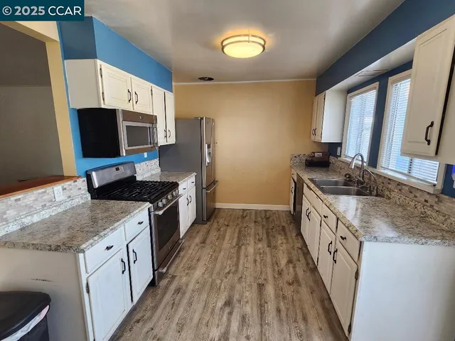 a kitchen with granite countertop a sink appliances cabinets and a counter top space