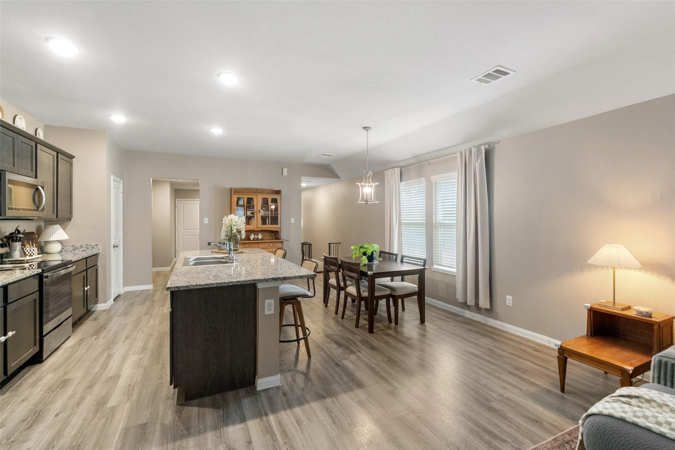 26431 Pin Oak Drive Hempstead, TX 77445 - Photo 11 of 32 Open-concept kitchen and dining area featuring a large granite island, modern lighting, and durable laminate flooring.