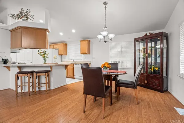 a dining room with wooden floor a chandelier a wooden table and chairs