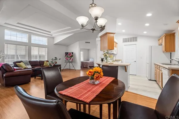 a dining room with wooden floor a chandelier a glass table and chairs