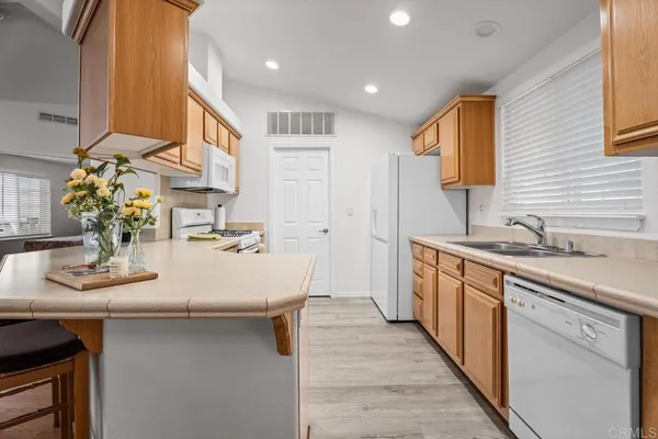 a large white kitchen with kitchen island a sink stainless steel appliances and cabinets