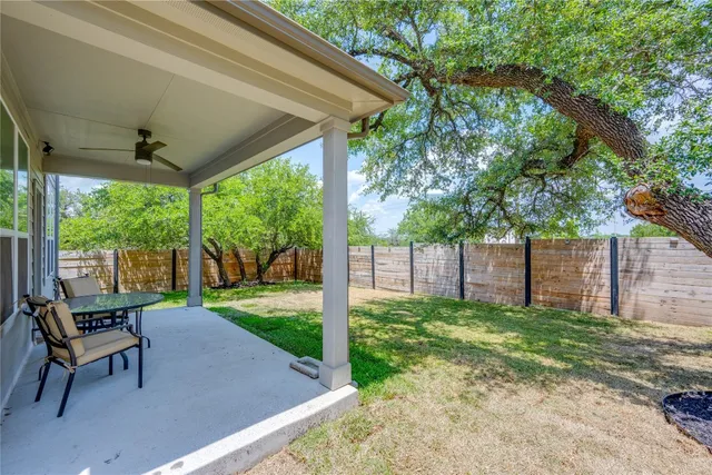 a view of a backyard with table and chair under a large tree
