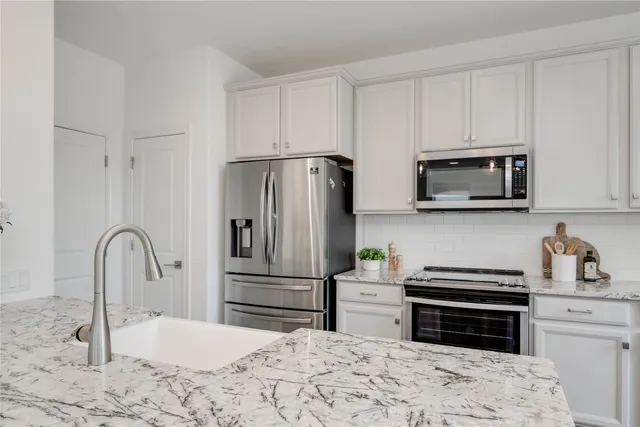 a kitchen with granite countertop a refrigerator stove and microwave