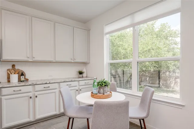 a kitchen with stainless steel appliances a white table chairs and a window