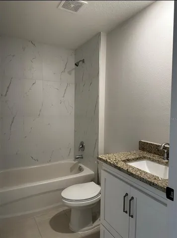 a bathroom with a granite countertop toilet sink and mirror