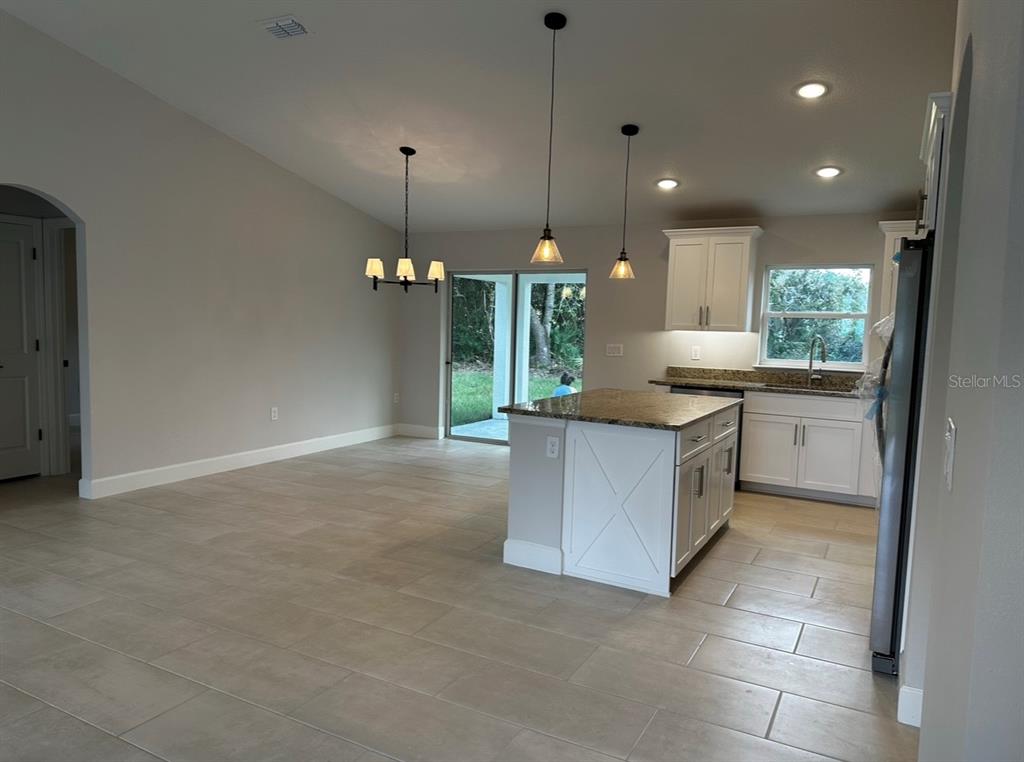 1450 5th Avenue DeLand, FL 32724 - Photo 14 of 16 a kitchen with kitchen island granite countertop a stove a sink a refrigerator and a counter top space