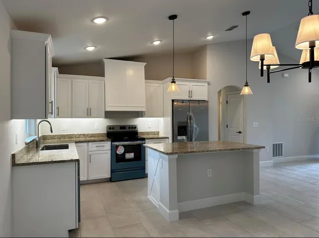a kitchen with stainless steel appliances granite countertop a sink a stove and a refrigerator