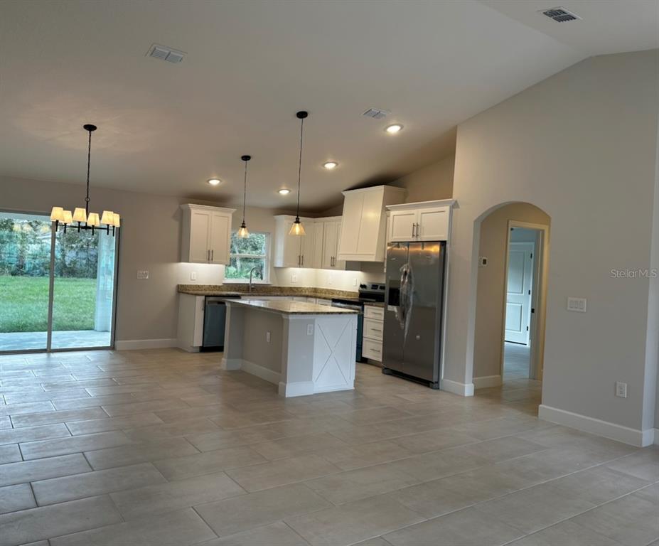 1450 5th Avenue DeLand, FL 32724 - Photo 3 of 16 a kitchen with stainless steel appliances kitchen island granite countertop a refrigerator a sink a stove and oven with wooden floor