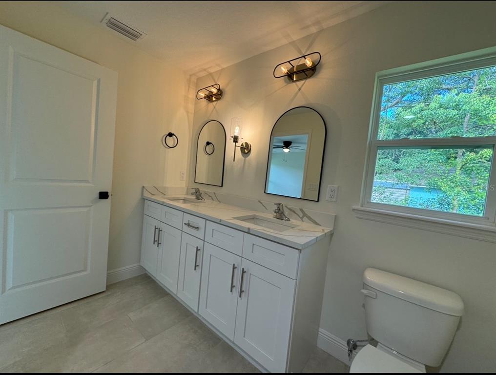 1450 5th Avenue DeLand, FL 32724 - Photo 4 of 16 a bathroom with a double vanity sink and mirror with window