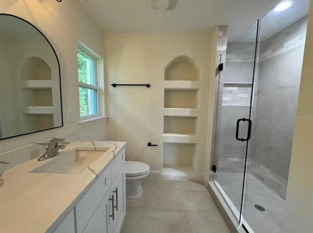 a bathroom with a granite countertop sink a toilet and shower