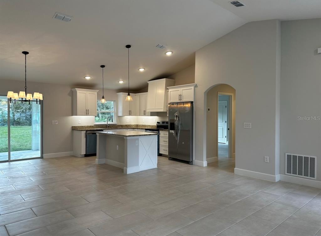 1450 5th Avenue DeLand, FL 32724 - Photo 9 of 16 a kitchen with stainless steel appliances kitchen island granite countertop a refrigerator a sink a stove and white cabinets with wooden floor
