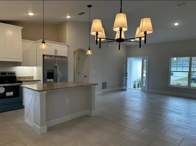 a kitchen with stainless steel appliances granite countertop a sink a stove and a wooden floors