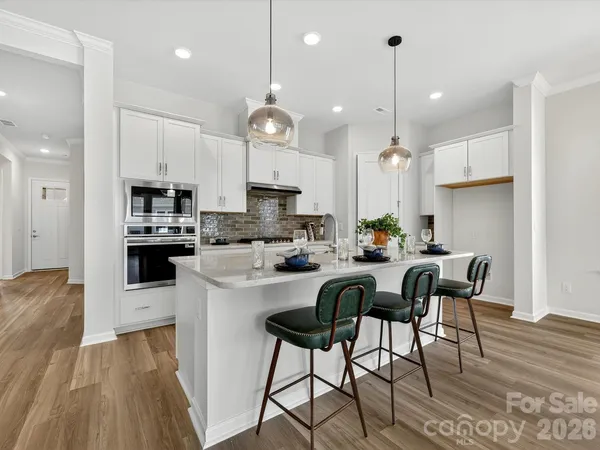 a kitchen with stainless steel appliances granite countertop a stove top oven a refrigerator a sink and chairs