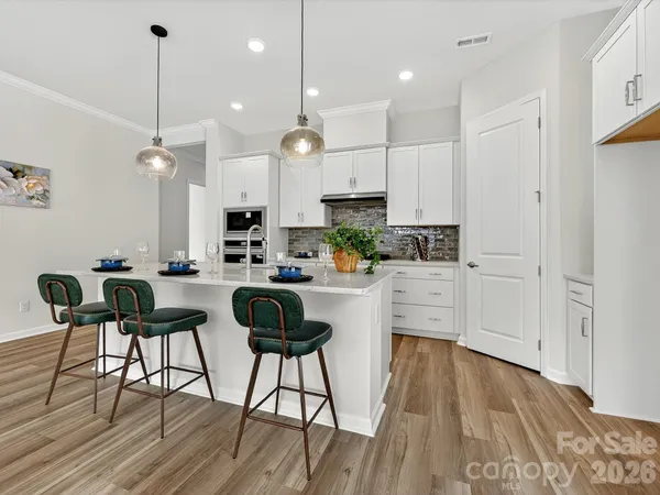 a kitchen with kitchen island wooden floors cabinets and stainless steel appliances