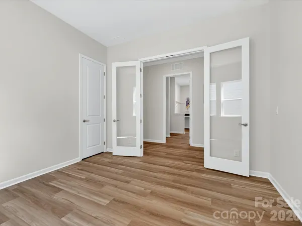 a view of an empty room with wooden floor and closet