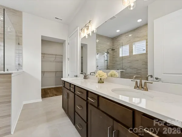 a spacious bathroom with a double vanity sink a mirror and a shower