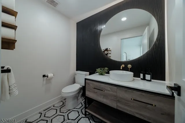 a bathroom with a granite countertop toilet a sink and mirror