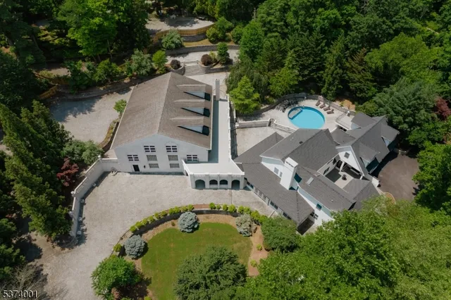 an aerial view of a house with outdoor space and trees all around