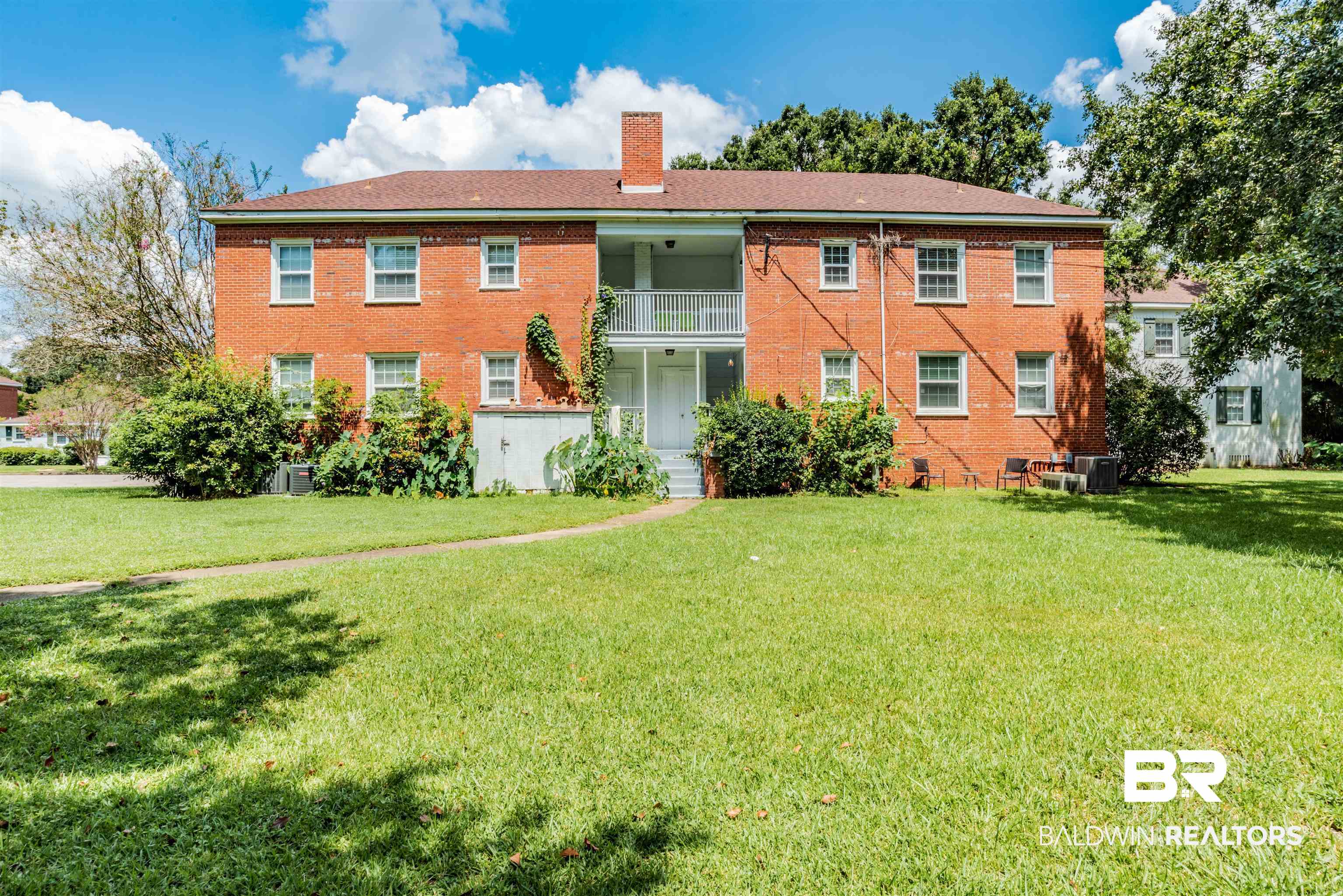 214 Upham Street, Unit 7C Mobile, AL 36607 - Photo 24 of 32 Rear view of property featuring brick siding, a chimney, a lawn, and a balcony