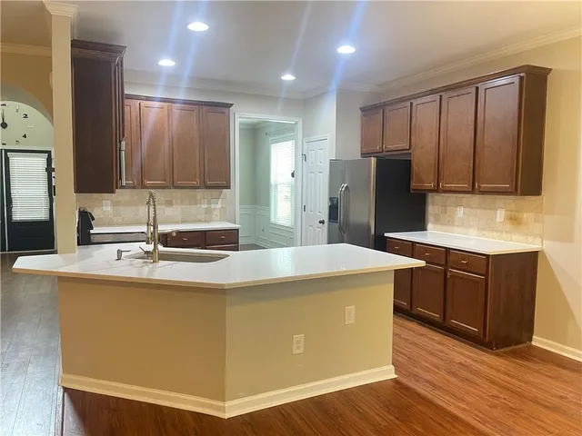 a kitchen with kitchen island granite countertop wooden cabinets and refrigerator