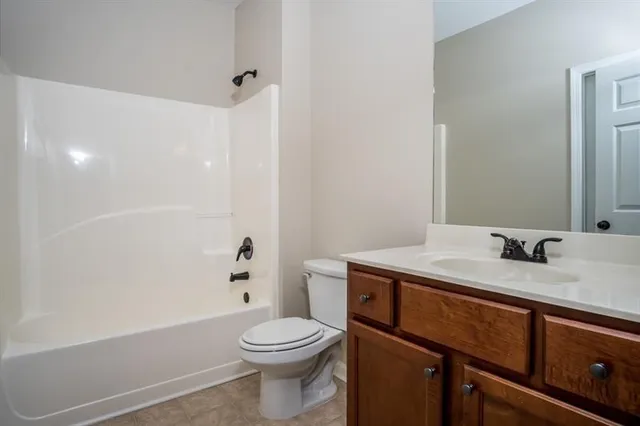 a bathroom with a granite countertop sink a toilet and shower