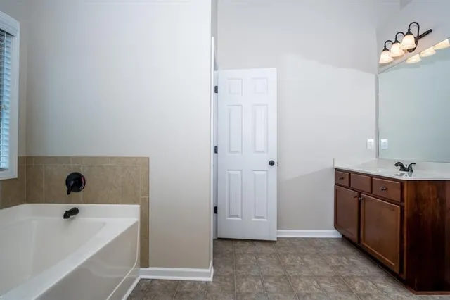 a bathroom with a tub a sink and mirror
