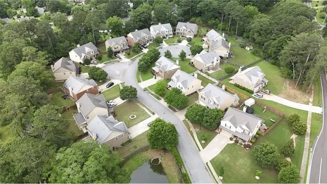 an aerial view of a house with a lot of flower plants and large trees