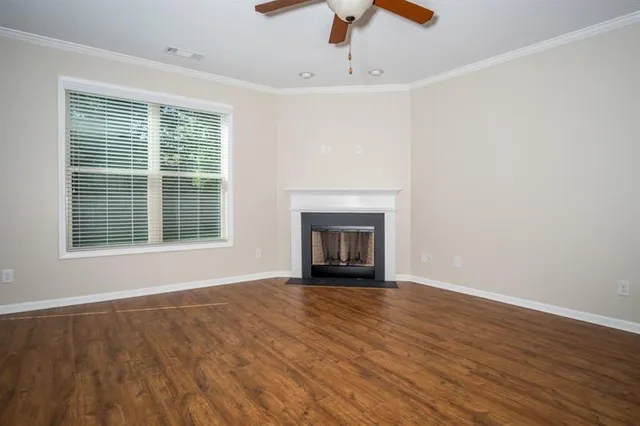 a view of an empty room with wooden floor fireplace and a window
