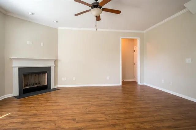 a view of an empty room with a fireplace and a ceiling fan